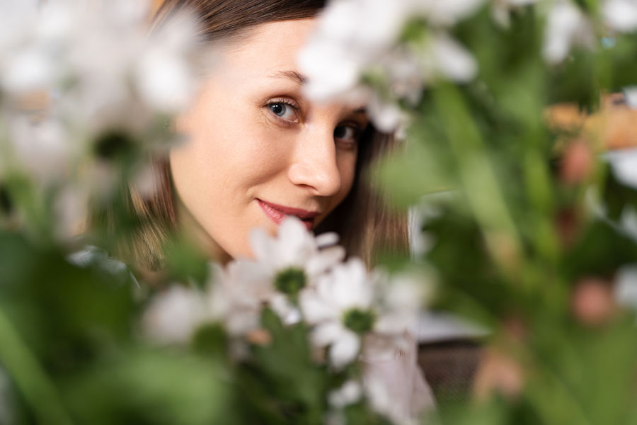 smiling-face-beautiful-young-woman-surrounded-by-white-flowers-green-leaves